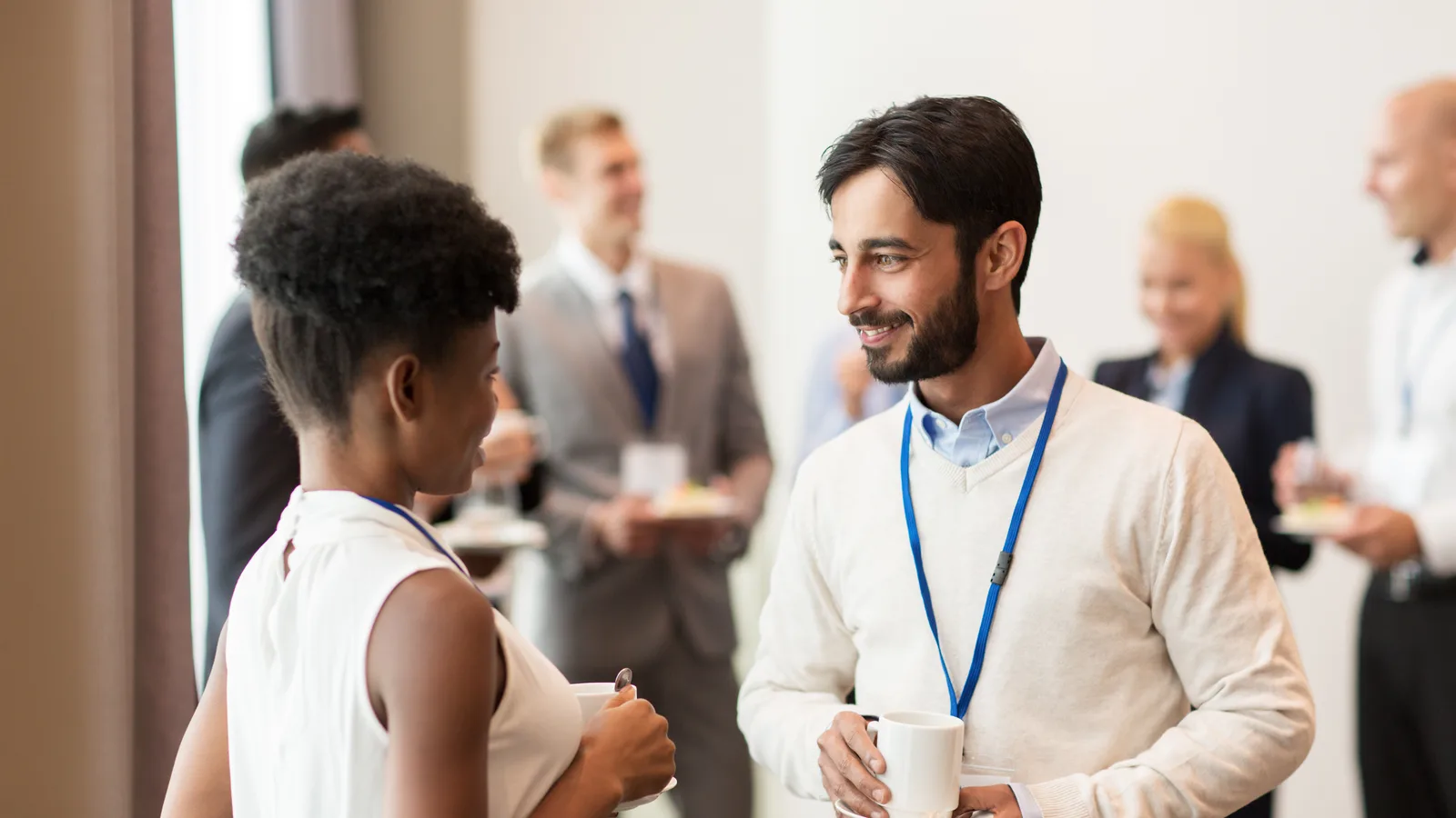 People with conference badges talking over coffee at a morning event