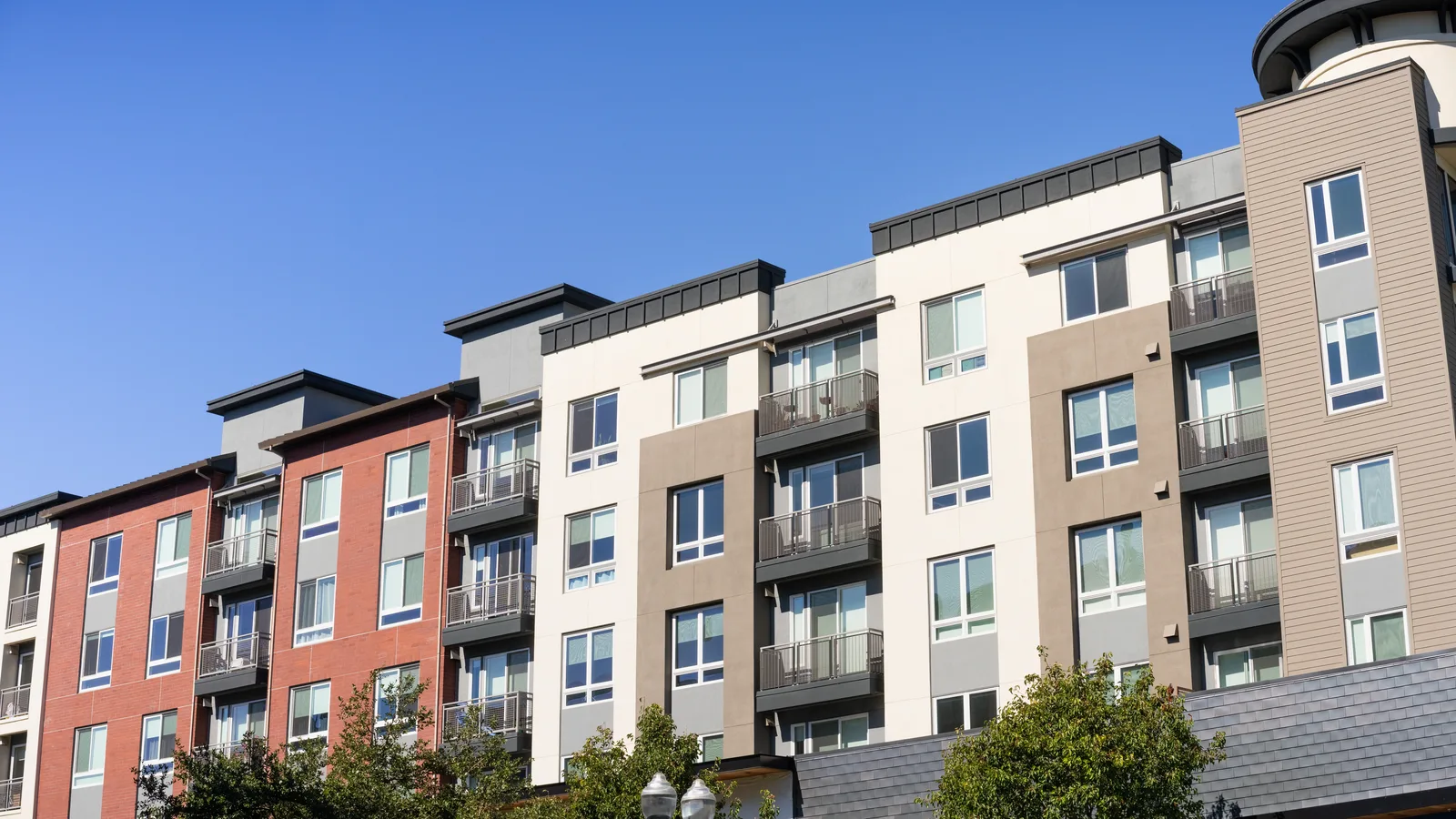 A four story apartment building with balconies under a clear blue sky