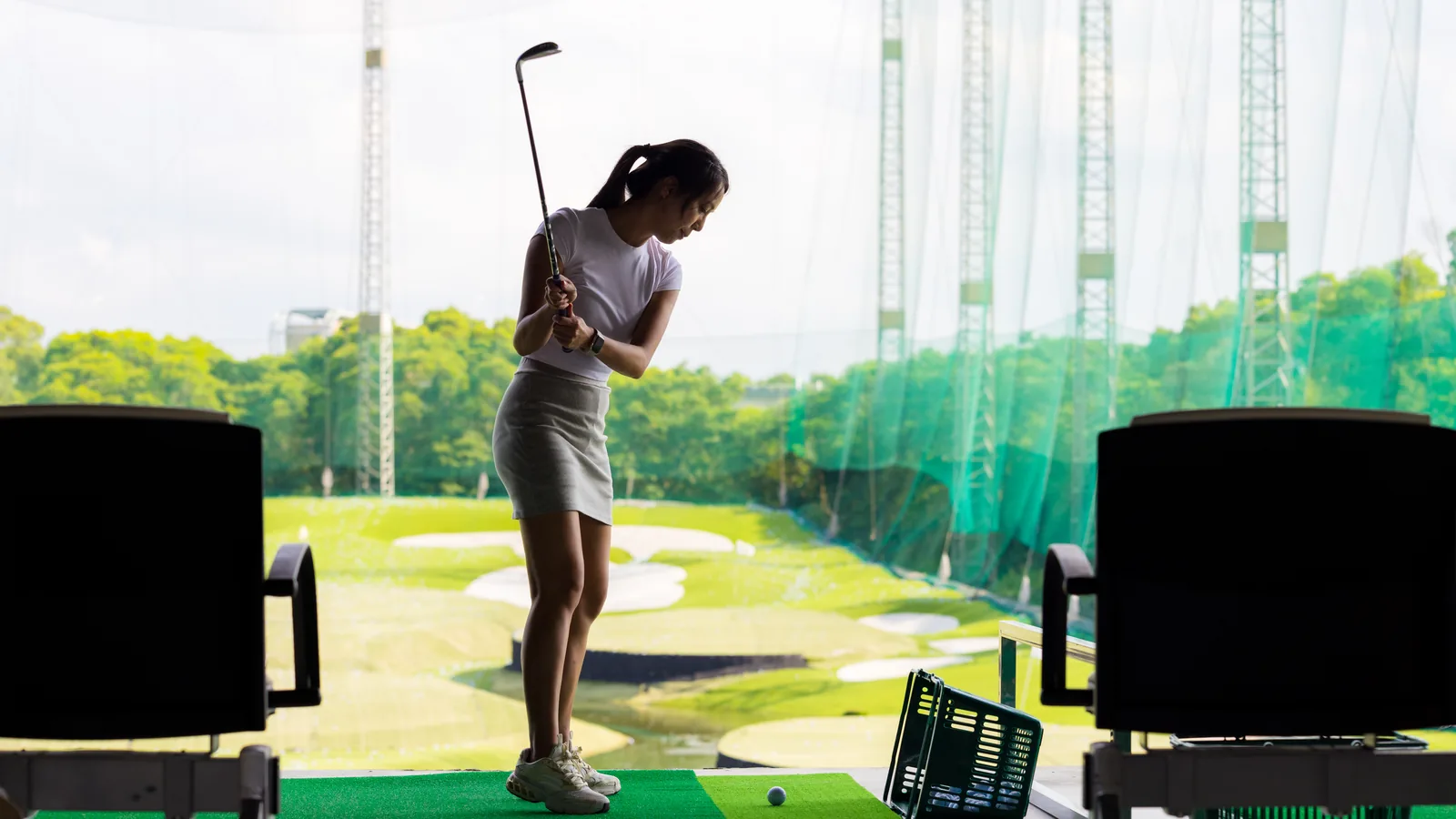 A golfer mid-swing in an indoor bay