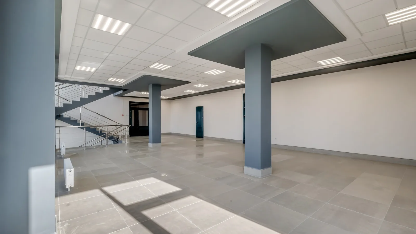 An empty open plan office floor with structural columns and a stairwell
