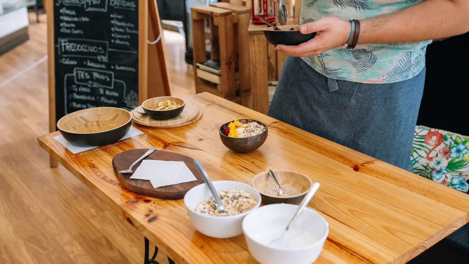 Bowls being assembled on a wooden counter in a bright cafe