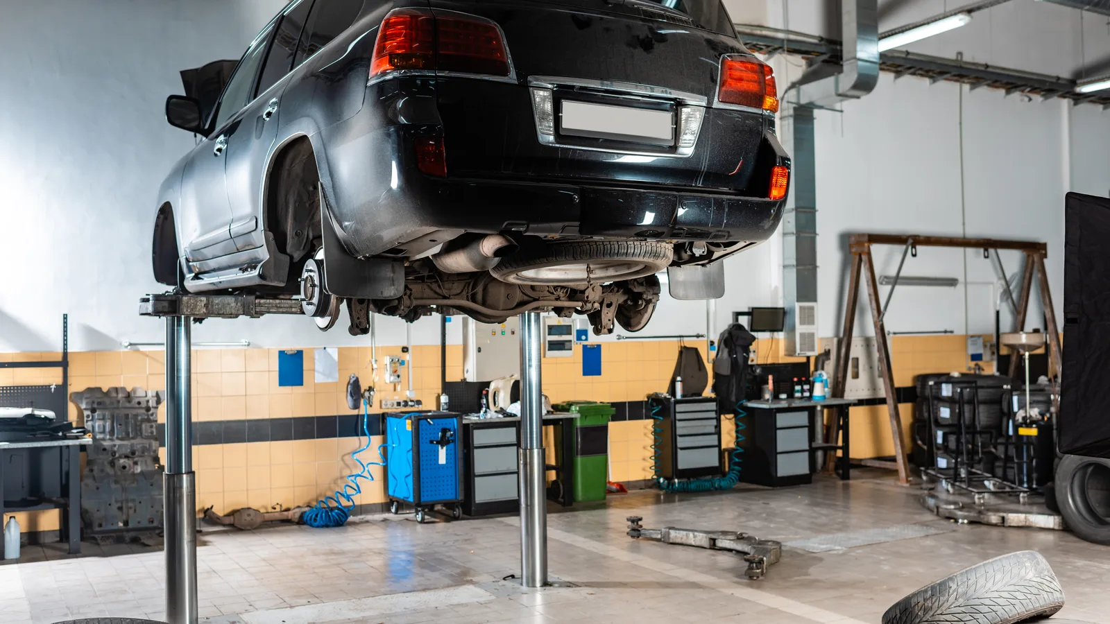 A car raised on a two post lift inside an auto service bay
