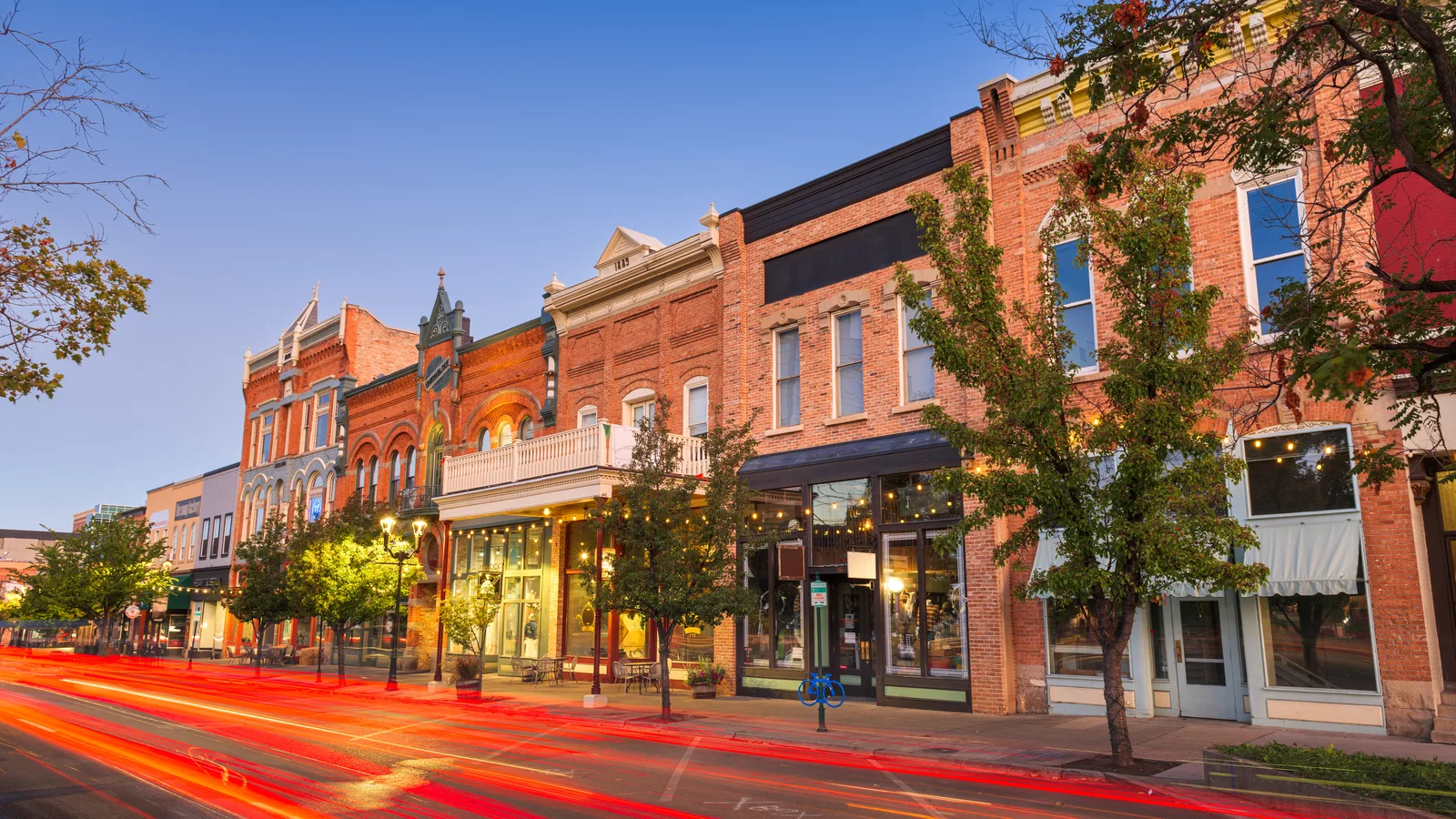 A row of brick commercial storefronts along a village street at twilight